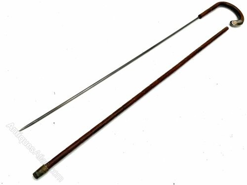 An antique gentlemens partridge wood walking stick unsheathed to reveal a long, thin steel blade.