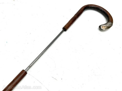 An antique gentlemens partridge wood walking stick unsheathed to reveal a long, thin steel blade. View IV