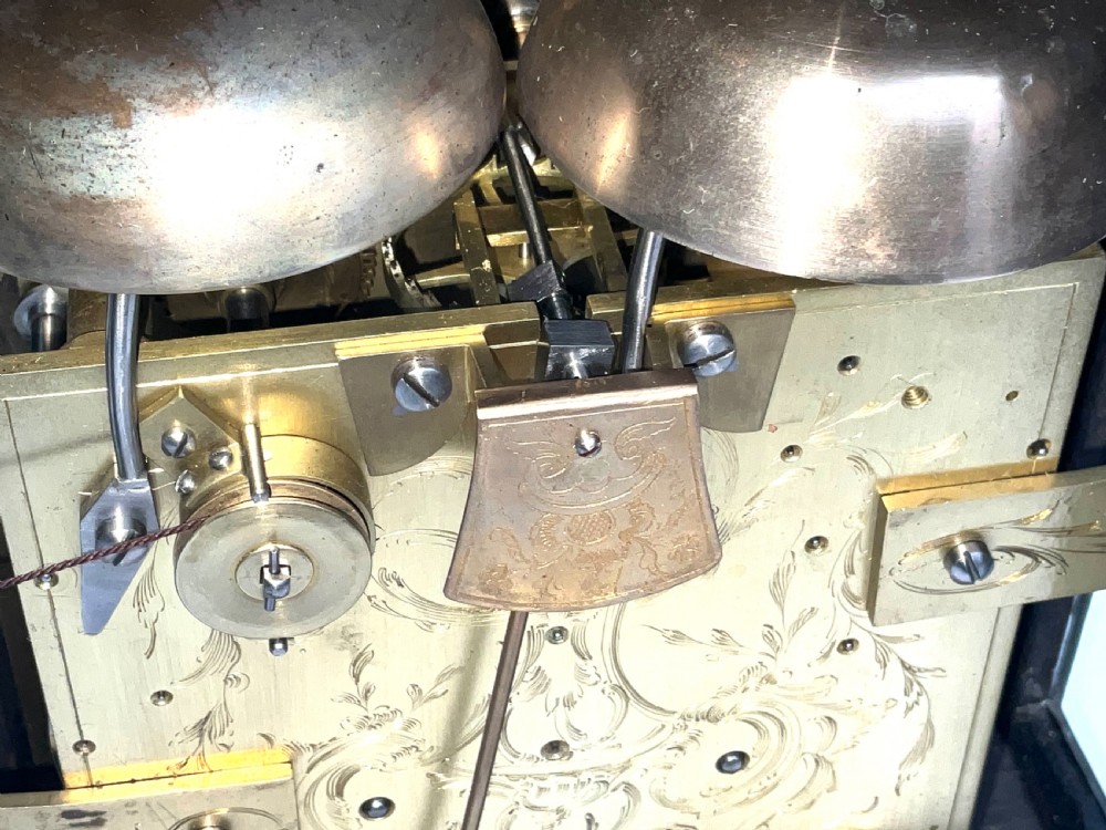 An eighteenth-century ebonised Georgian bracket clock featuring a brass carrying handle, an arched glass front door, and a brass dial with silvered chapter ring. View XI