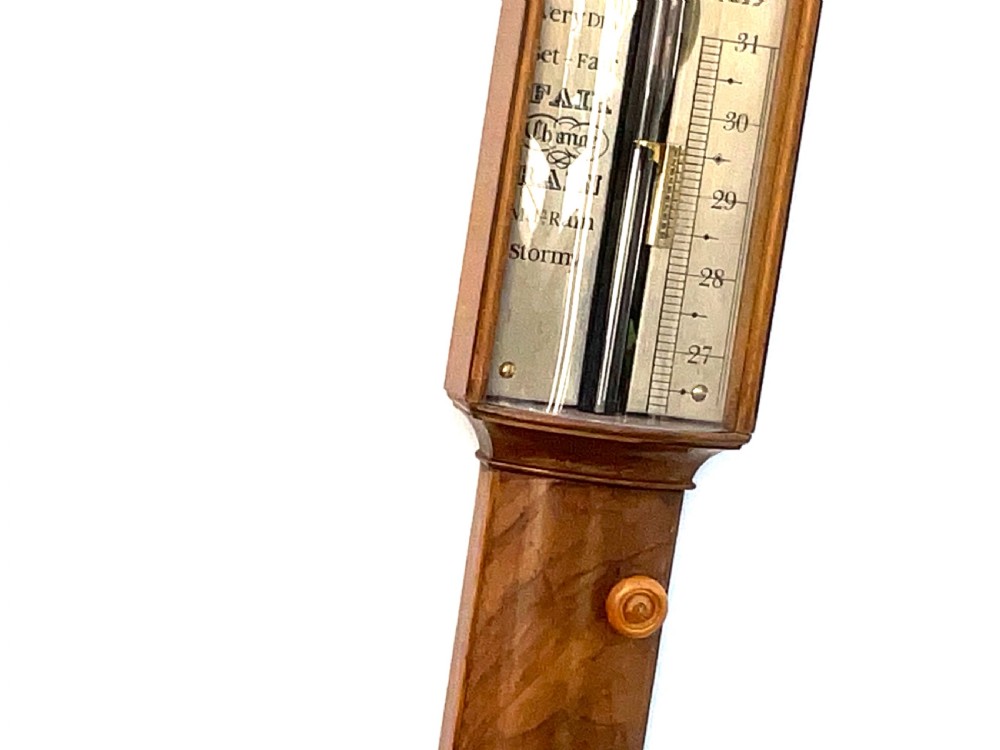 A wall-mounted antique Georgian stick barometer crafted from figured satinwood, featuring a brass finial, pediment top, and glass-fronted silvered scale. View XI