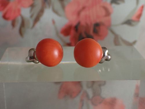 fig 1. A pair of round, polished orange coral stud-style clip-on earrings mounted on silver backings.