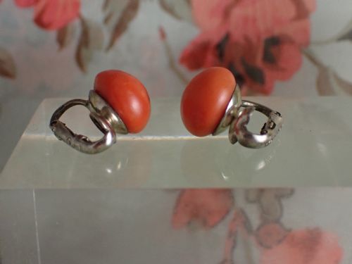fig 2. A pair of round, polished orange coral stud-style clip-on earrings mounted on silver backings.