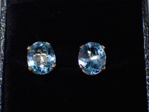 fig 2. A pair of vintage gold stud earrings featuring oval-cut light blue aquamarine gemstones held within four-prong claw settings.