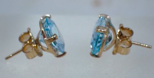 fig 3. A pair of vintage gold stud earrings featuring oval-cut light blue aquamarine gemstones held within four-prong claw settings.