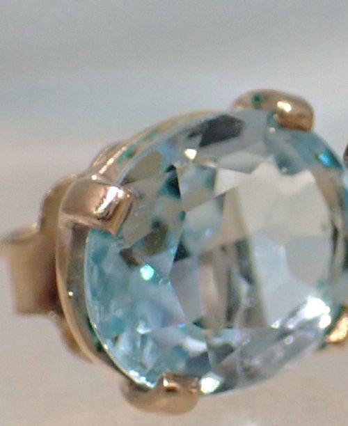 A pair of vintage gold stud earrings featuring oval-cut light blue aquamarine gemstones held within four-prong claw settings. View VI