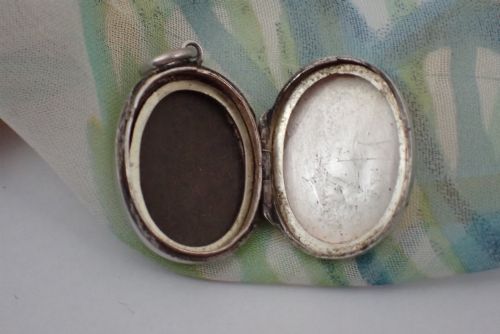 fig 3. An oval sterling silver locket decorated with a central relief horseshoe motif surrounded by hand-engraved leaf patterns and fitted with a top jump ring.