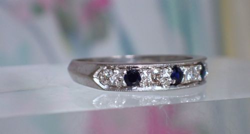fig 1. A vintage 18ct white gold half eternity ring featuring alternating round dark blue sapphires and clear diamonds along the band.