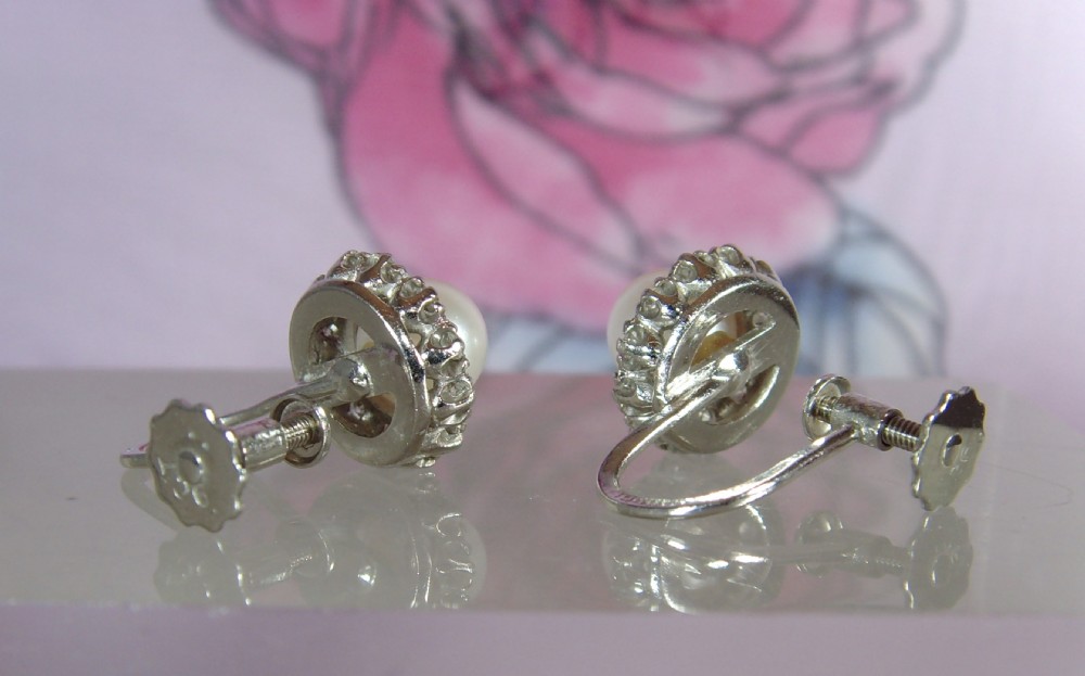 A pair of mid-century 9ct white gold cluster earrings featuring central round pearls encircled by small diamonds with screw-back fittings. View IV