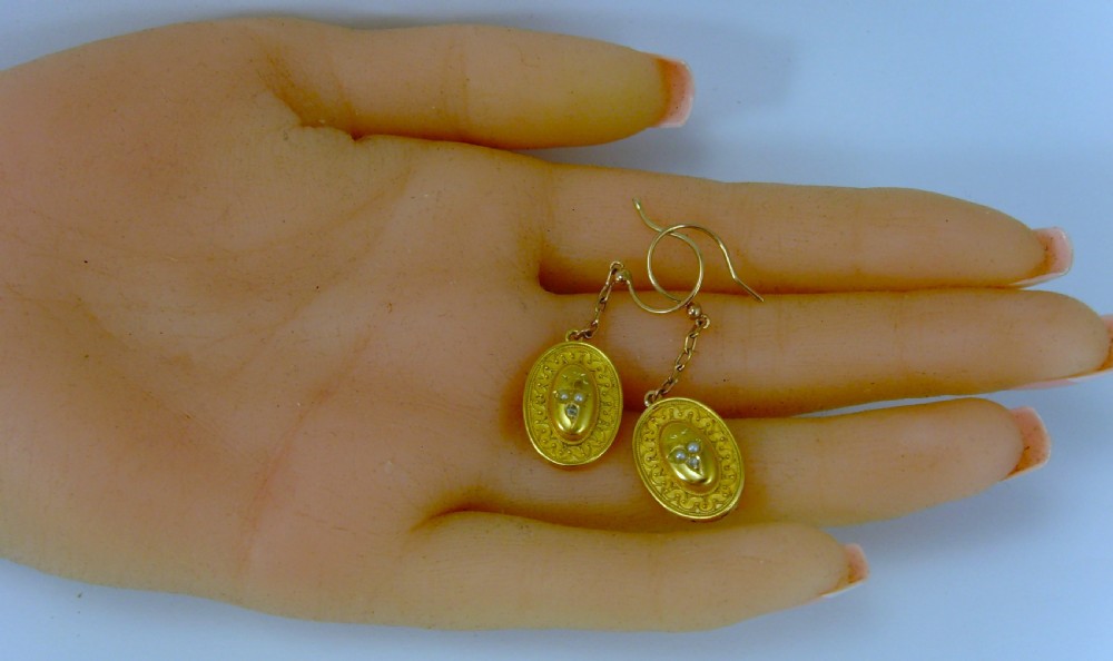 A pair of Victorian Etruscan Revival yellow gold oval drop earrings featuring central wirework detailing with seed pearls and diamonds suspended from chain links. View II