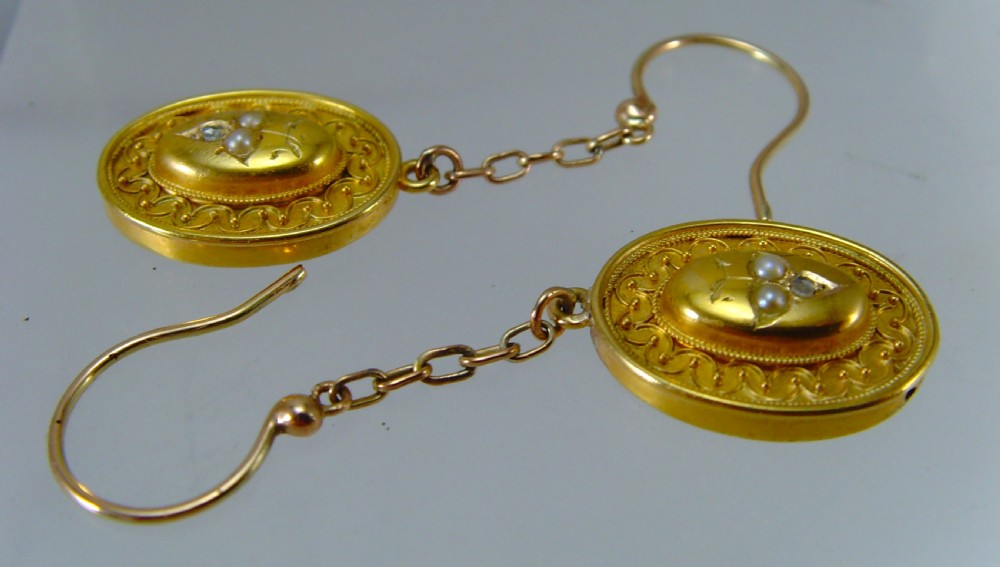 A pair of Victorian Etruscan Revival yellow gold oval drop earrings featuring central wirework detailing with seed pearls and diamonds suspended from chain links. View IV