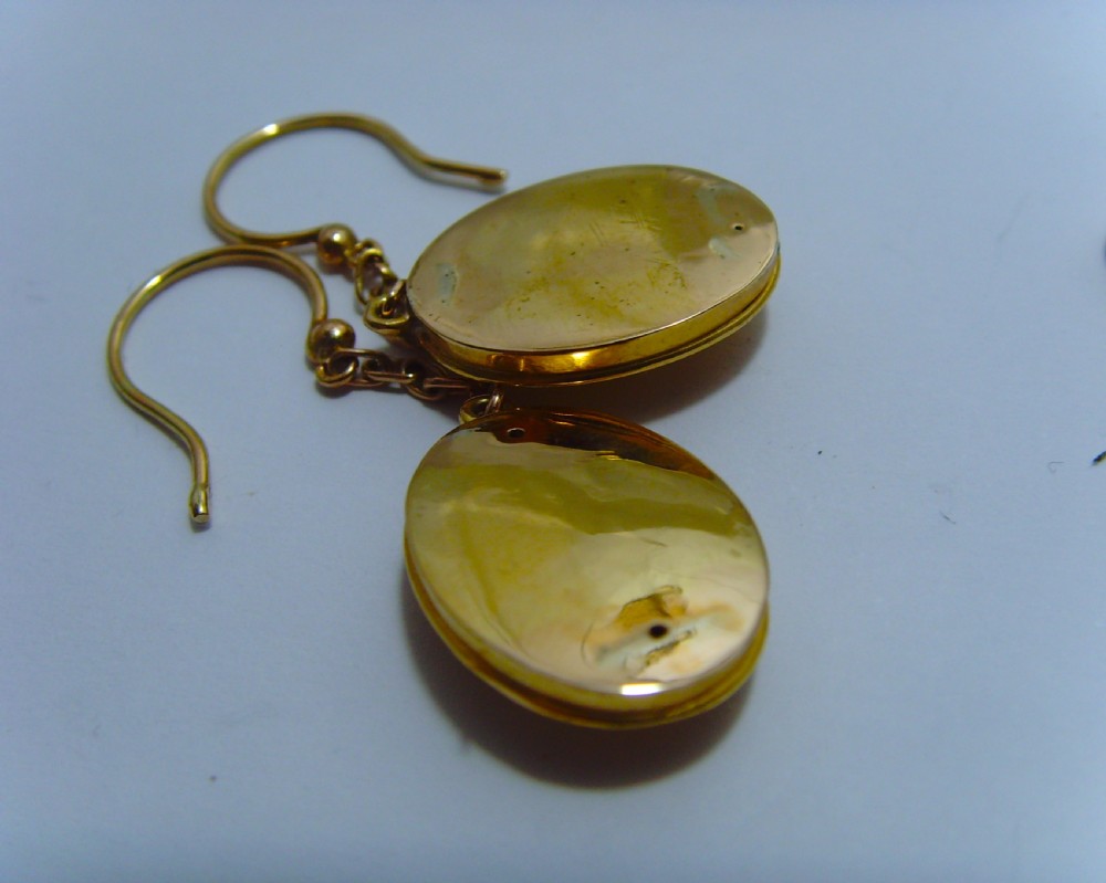 A pair of Victorian Etruscan Revival yellow gold oval drop earrings featuring central wirework detailing with seed pearls and diamonds suspended from chain links. View VI
