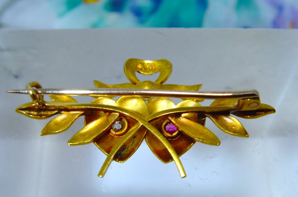 A Victorian 18ct yellow gold double heart brooch set with a ruby, a diamond, and seed pearl accents. View IV