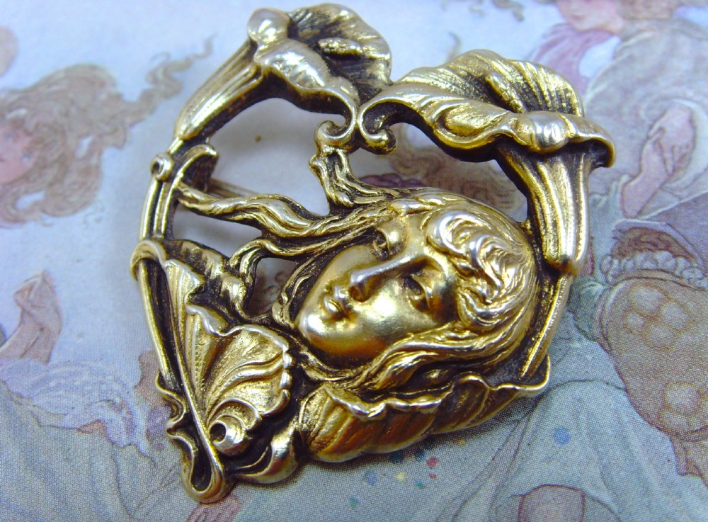 A heart-shaped silver and gold-gilt Art Nouveau brooch depicting a female portrait with flowing hair amidst botanical leaf forms. View II