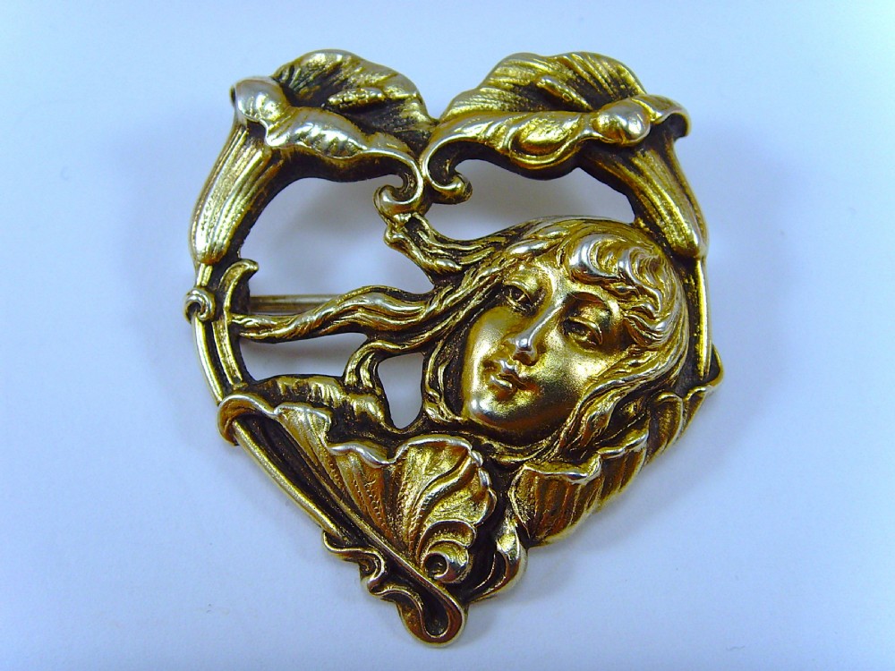 A heart-shaped silver and gold-gilt Art Nouveau brooch depicting a female portrait with flowing hair amidst botanical leaf forms. View III