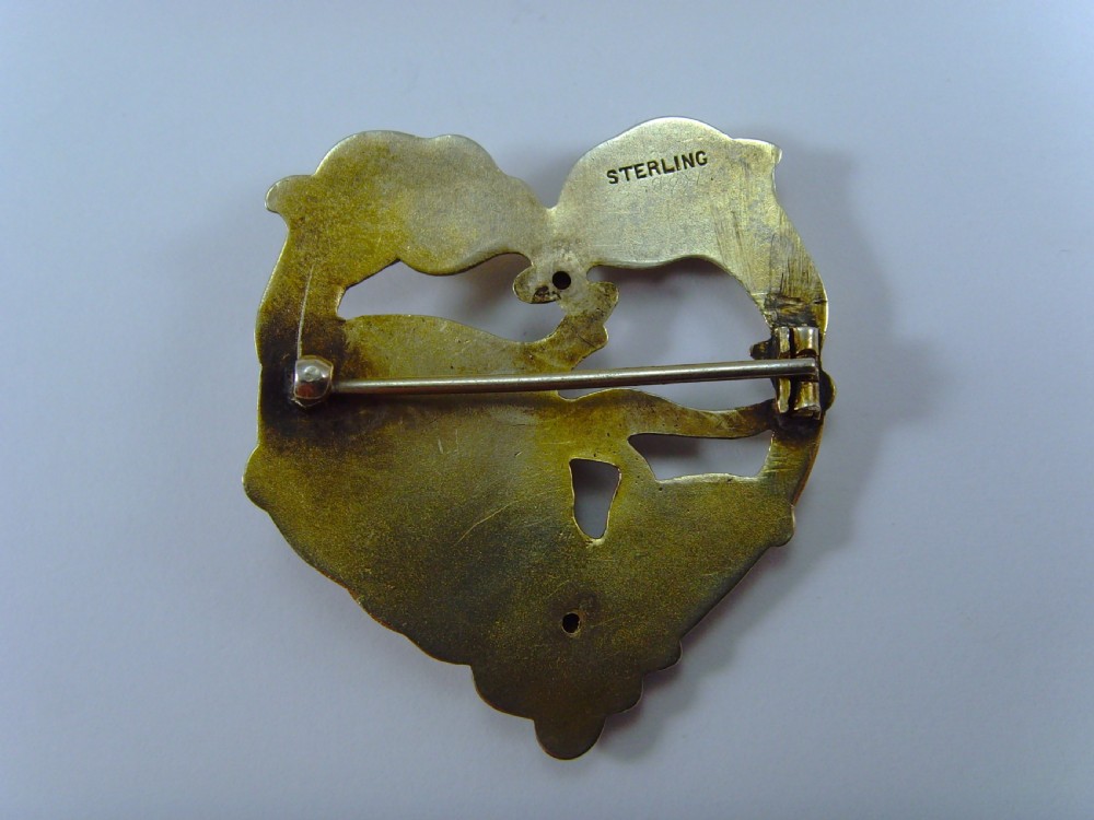 A heart-shaped silver and gold-gilt Art Nouveau brooch depicting a female portrait with flowing hair amidst botanical leaf forms. View VI