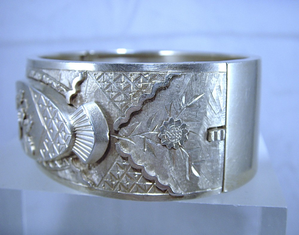 A wide Victorian sterling silver hinged cuff bangle featuring engraved floral motifs, geometric patterns, and fan details. View II