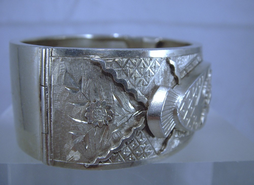 A wide Victorian sterling silver hinged cuff bangle featuring engraved floral motifs, geometric patterns, and fan details. View V
