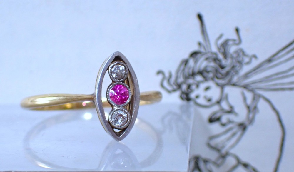An Art Deco 18ct yellow gold and platinum ring featuring a vertical marquise bezel setting with a central round ruby flanked by two diamonds. View II