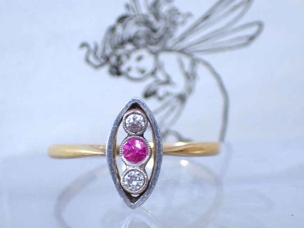 An Art Deco 18ct yellow gold and platinum ring featuring a vertical marquise bezel setting with a central round ruby flanked by two diamonds. View III