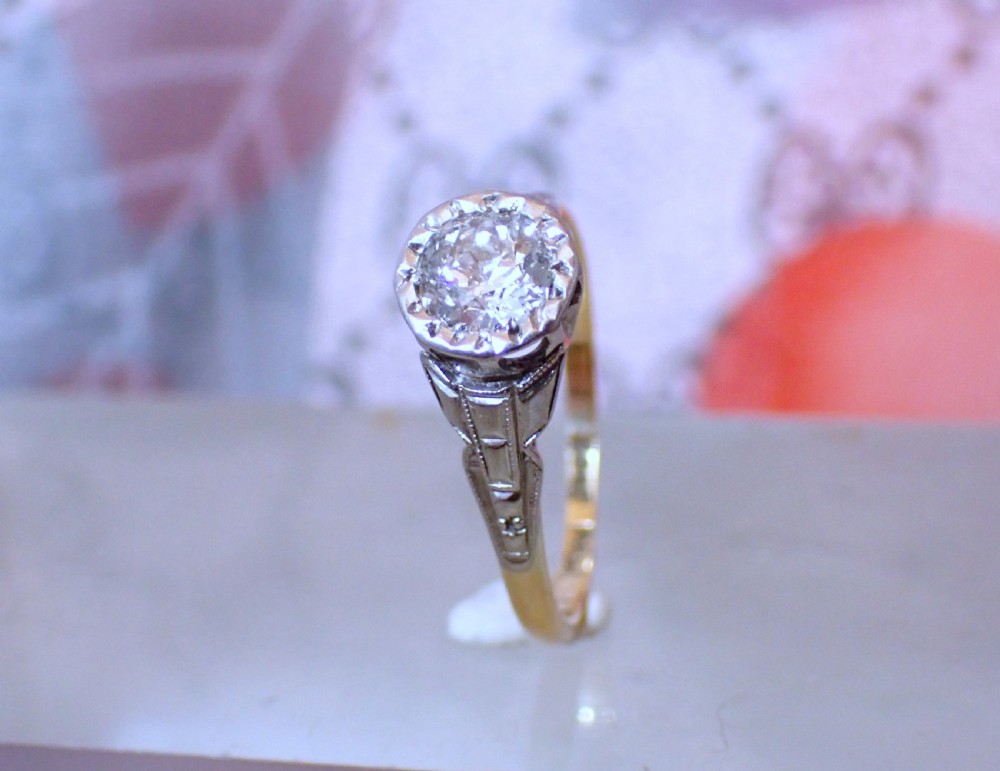 An Art Deco ring with a central diamond set in a platinum geometric head on an 18ct yellow gold band. View II