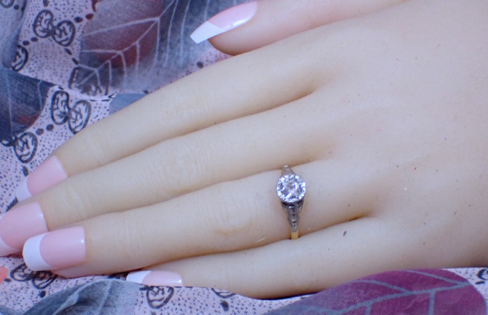 An Art Deco ring with a central diamond set in a platinum geometric head on an 18ct yellow gold band. View VII