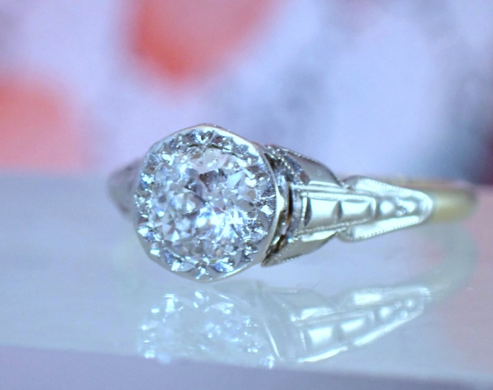 An Art Deco ring with a central diamond set in a platinum geometric head on an 18ct yellow gold band. View IX