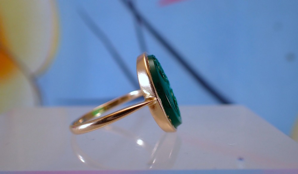 An Art Deco gold ring set with an oval green chalcedony gemstone featuring low-relief floral and scroll carving. View IV