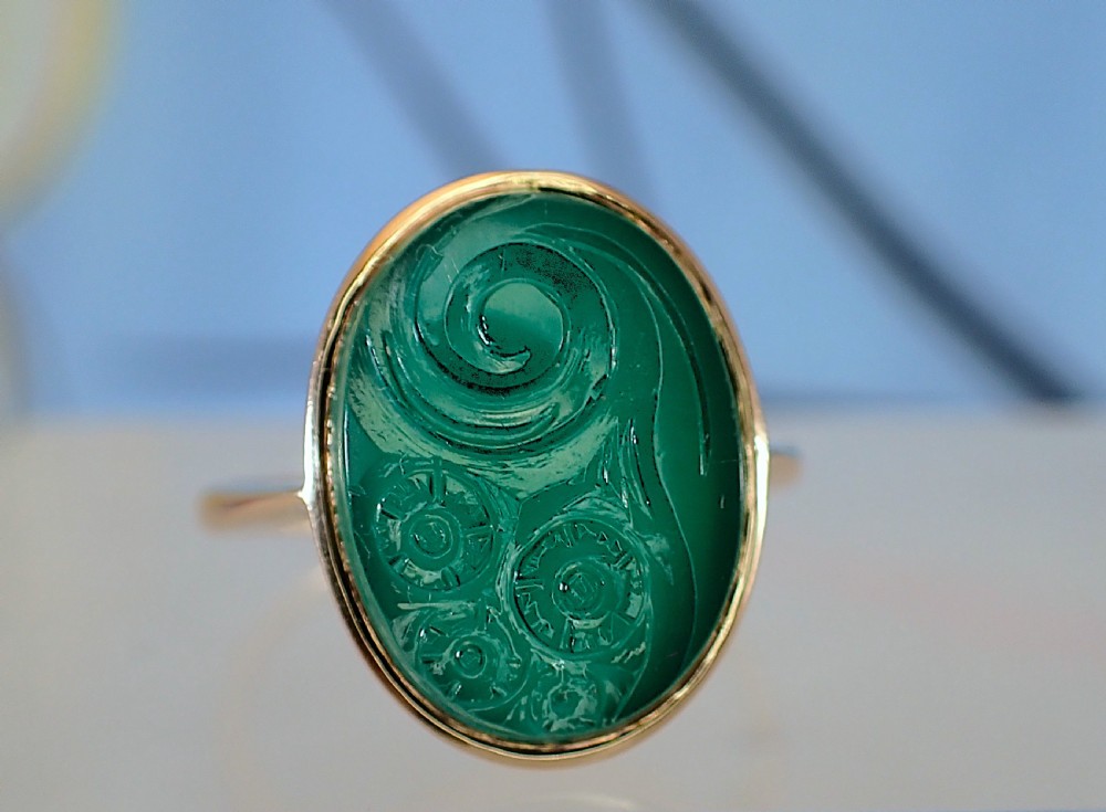 An Art Deco gold ring set with an oval green chalcedony gemstone featuring low-relief floral and scroll carving. View VII