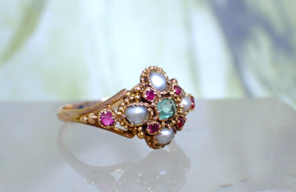 A Georgian 15ct gold ring featuring a central emerald framed by rubies and pearls in a cluster setting on a split-shank band. View II