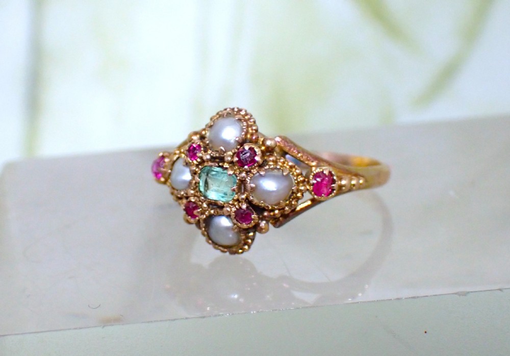 A Georgian 15ct gold ring featuring a central emerald framed by rubies and pearls in a cluster setting on a split-shank band. View IV