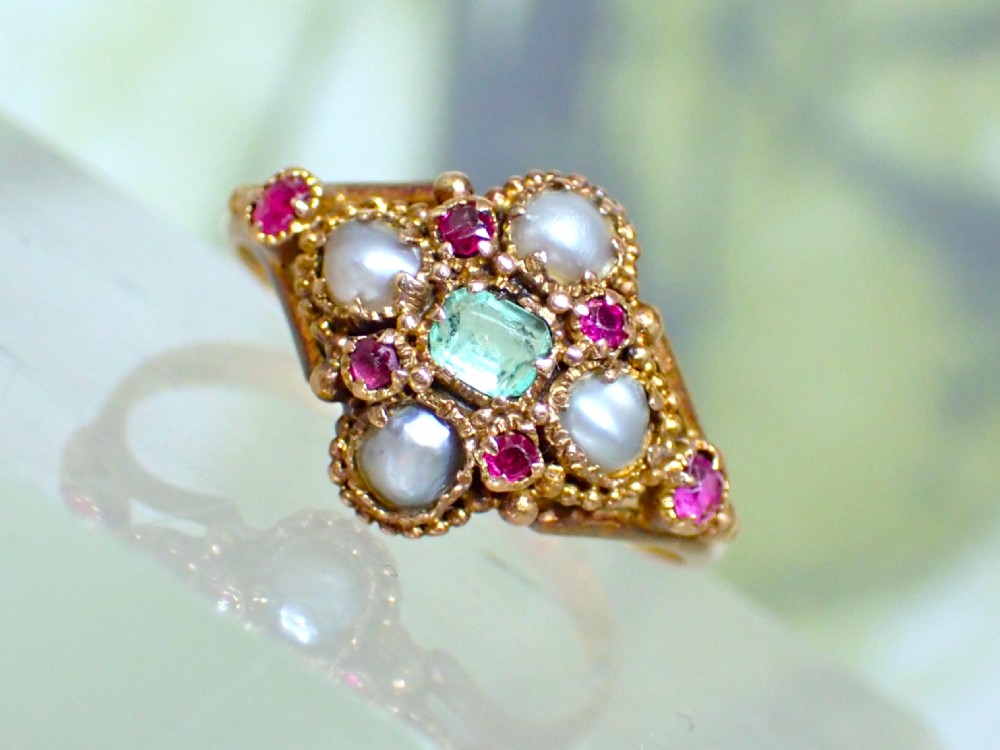 A Georgian 15ct gold ring featuring a central emerald framed by rubies and pearls in a cluster setting on a split-shank band. View V