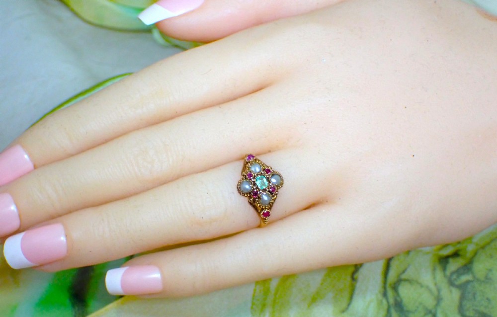 A Georgian 15ct gold ring featuring a central emerald framed by rubies and pearls in a cluster setting on a split-shank band. View VII