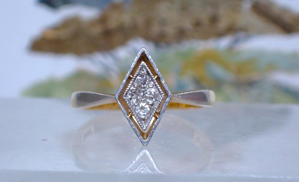 An Art Deco ring featuring a diamond-shaped lozenge motif set with four diamonds in platinum on an 18ct yellow gold band.