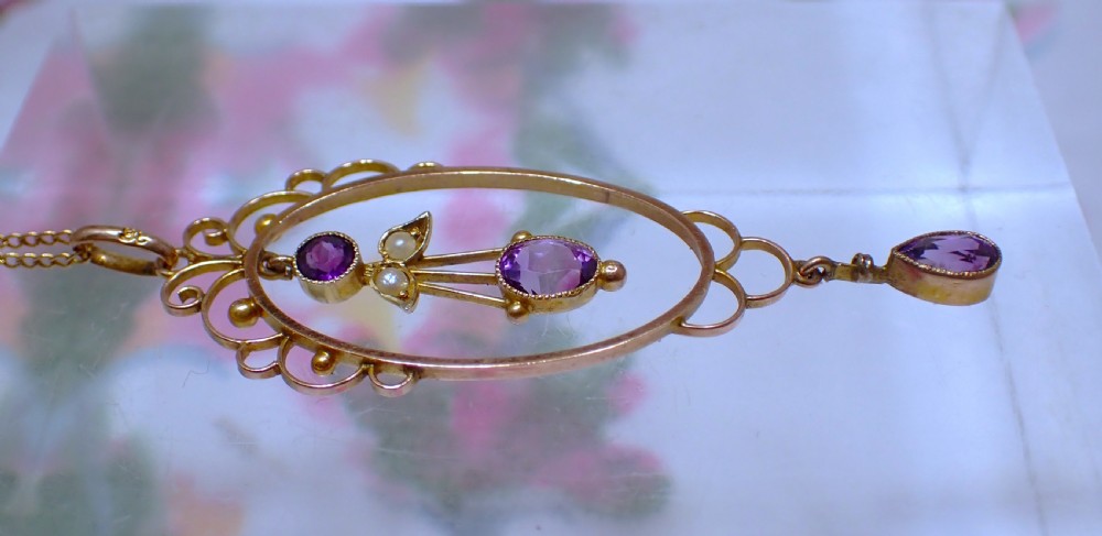 An Art Nouveau 9ct gold openwork oval pendant set with three purple amethysts and seed pearls suspended on a gold chain. View III