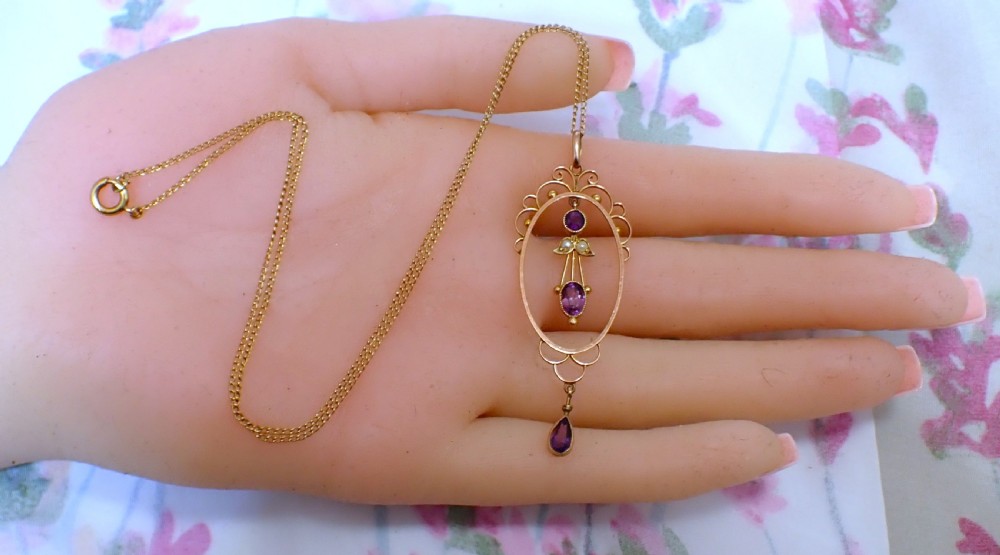 An Art Nouveau 9ct gold openwork oval pendant set with three purple amethysts and seed pearls suspended on a gold chain. View VI