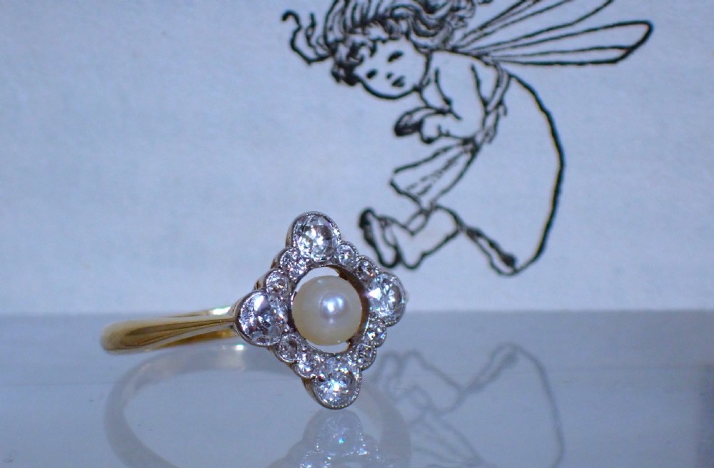 An antique Edwardian ring featuring a central natural pearl surrounded by a pierced diamond-set lozenge frame on an 18ct gold band. View VI