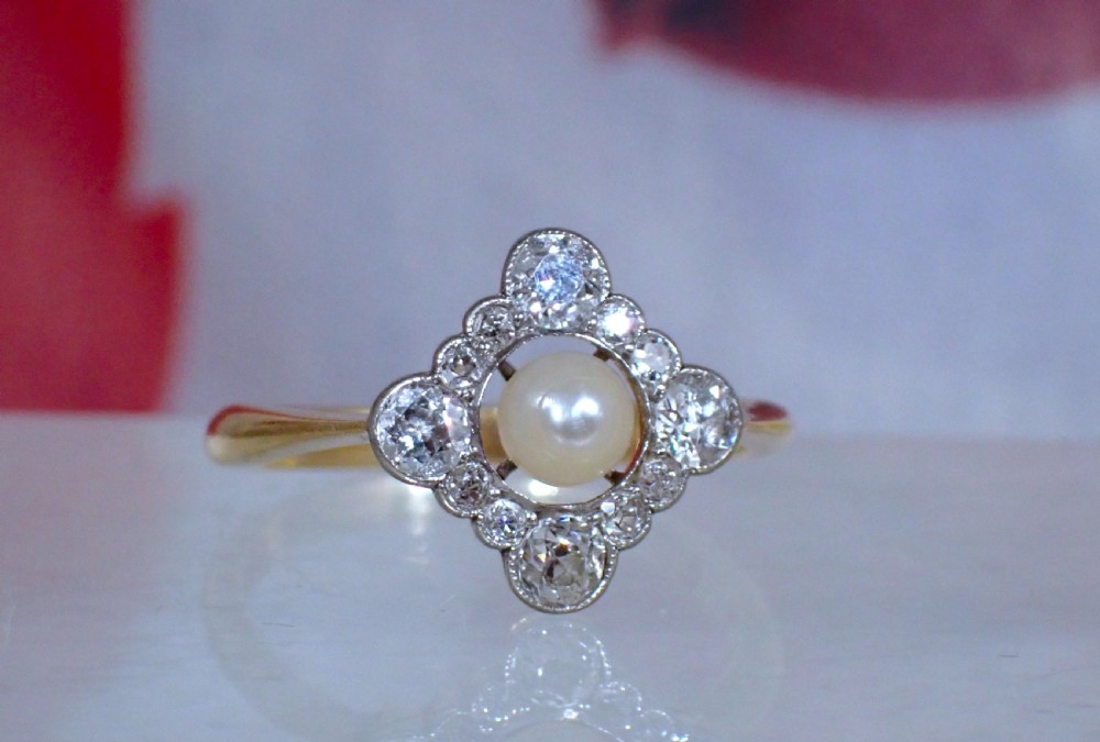 An antique Edwardian ring featuring a central natural pearl surrounded by a pierced diamond-set lozenge frame on an 18ct gold band. View VII