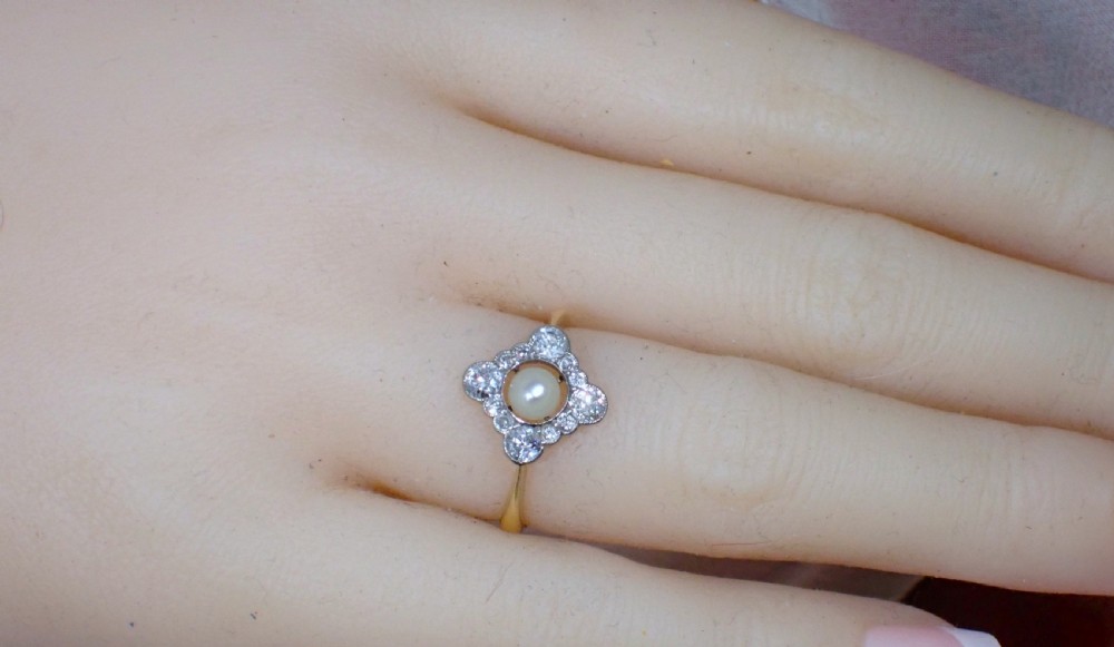 An antique Edwardian ring featuring a central natural pearl surrounded by a pierced diamond-set lozenge frame on an 18ct gold band. View IX