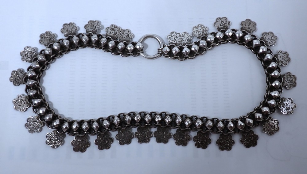 A Victorian silver collar necklace featuring woven link chain strands embellished with faceted beads and dangling engraved floral charms. View III