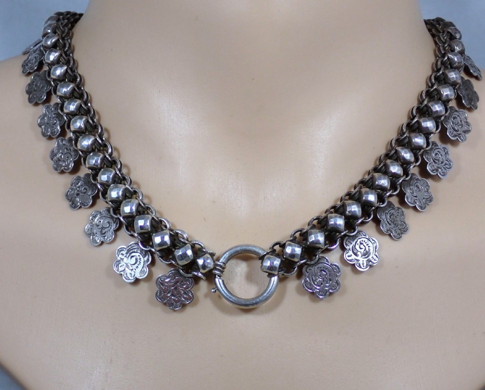 A Victorian silver collar necklace featuring woven link chain strands embellished with faceted beads and dangling engraved floral charms. View IV