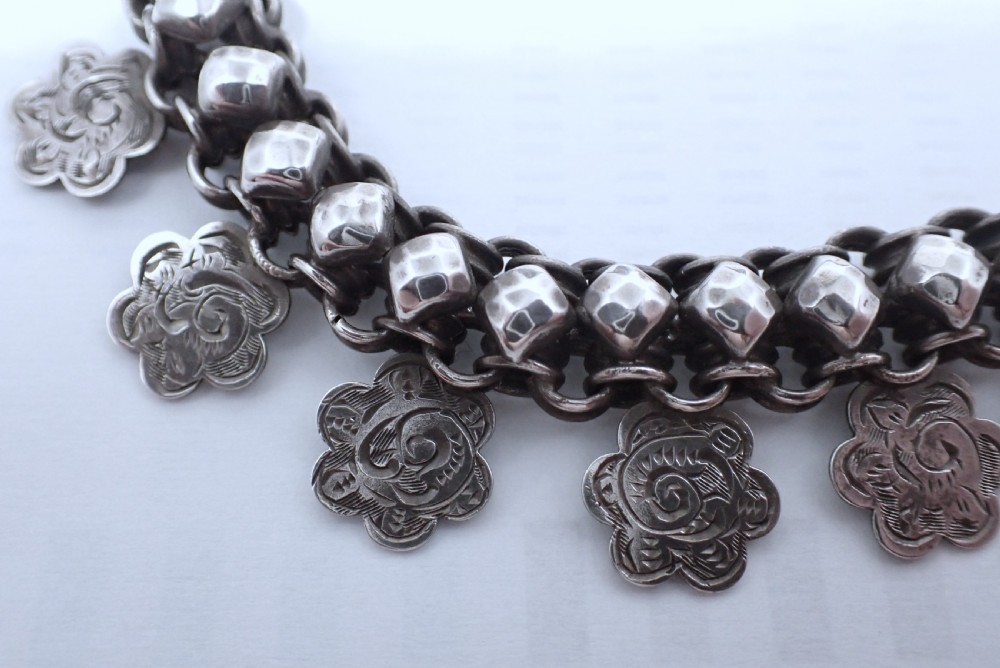 A Victorian silver collar necklace featuring woven link chain strands embellished with faceted beads and dangling engraved floral charms. View V