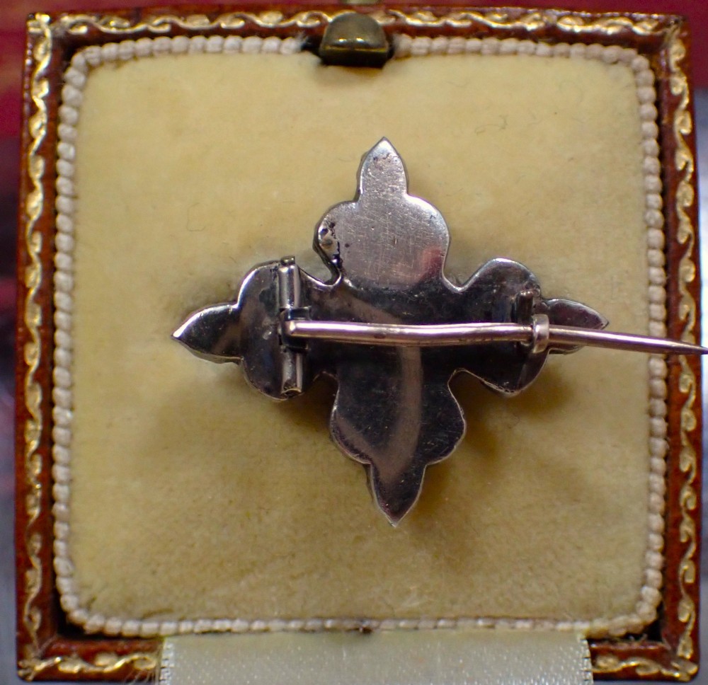 A cruciform Georgian brooch set with silver-topped black dot paste stones around a central rectangular pink ruby-coloured paste gem. View IV