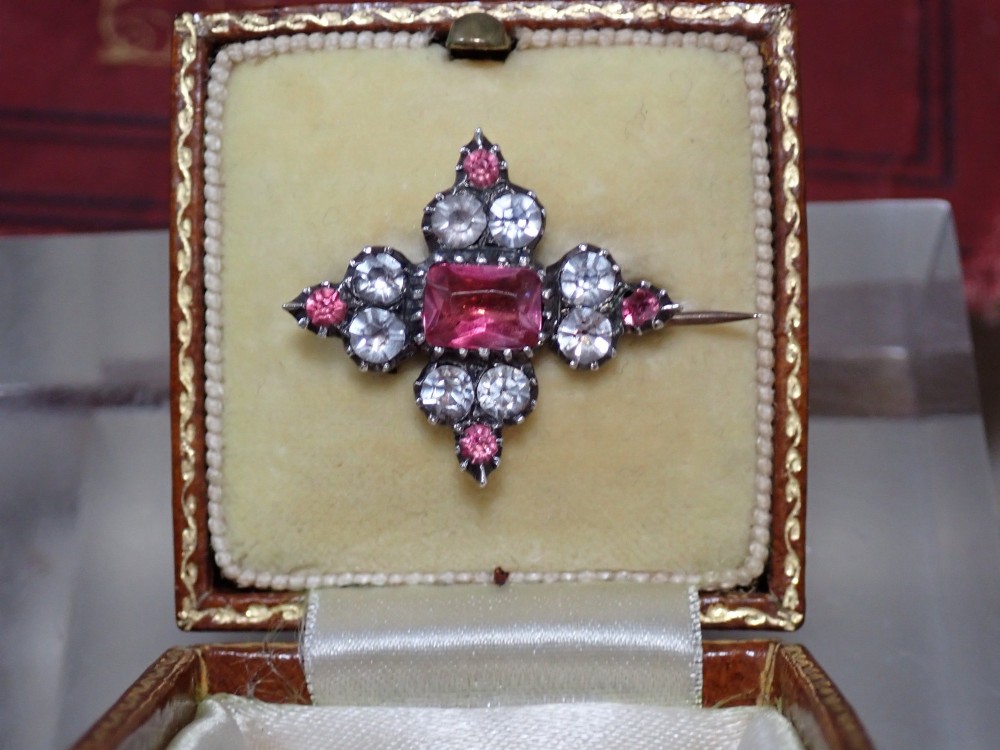 A cruciform Georgian brooch set with silver-topped black dot paste stones around a central rectangular pink ruby-coloured paste gem. View V