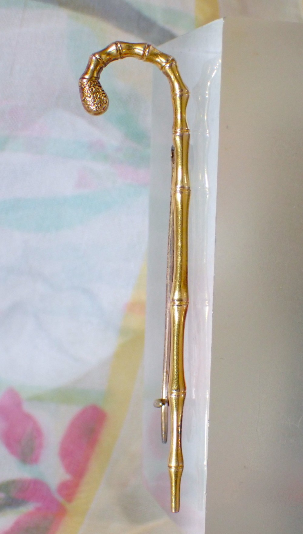 An Edwardian 15ct yellow gold brooch rendered in the shape of a bamboo walking cane with a textured crook handle. View II