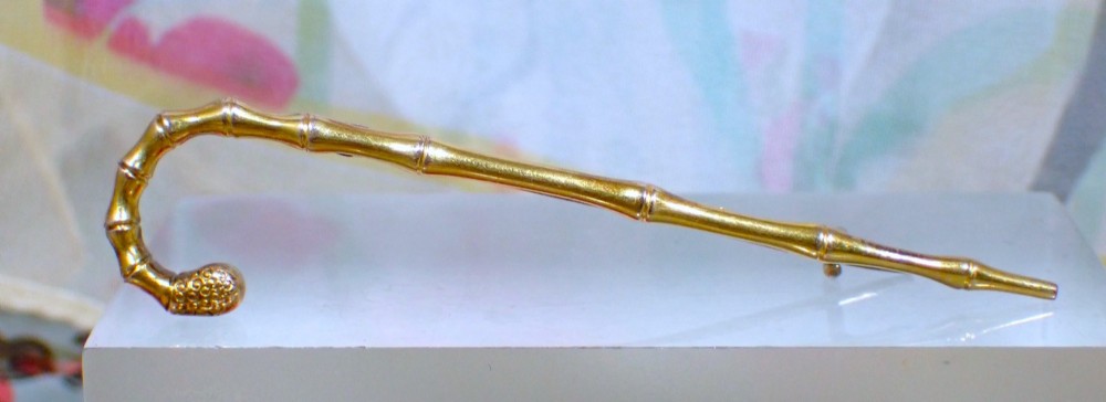 An Edwardian 15ct yellow gold brooch rendered in the shape of a bamboo walking cane with a textured crook handle. View IV