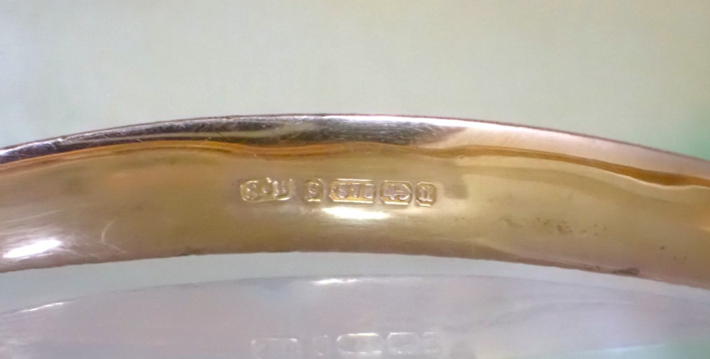 An antique Victorian hinged gold bangle featuring a textured honeycomb pattern across the upper band with a side safety chain. View V