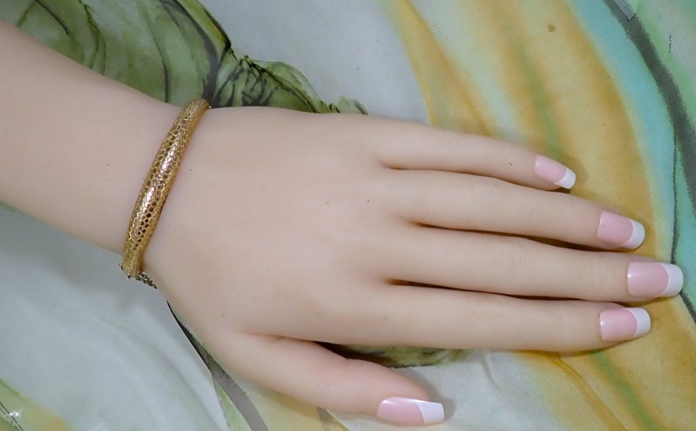 An antique Victorian hinged gold bangle featuring a textured honeycomb pattern across the upper band with a side safety chain. View VI