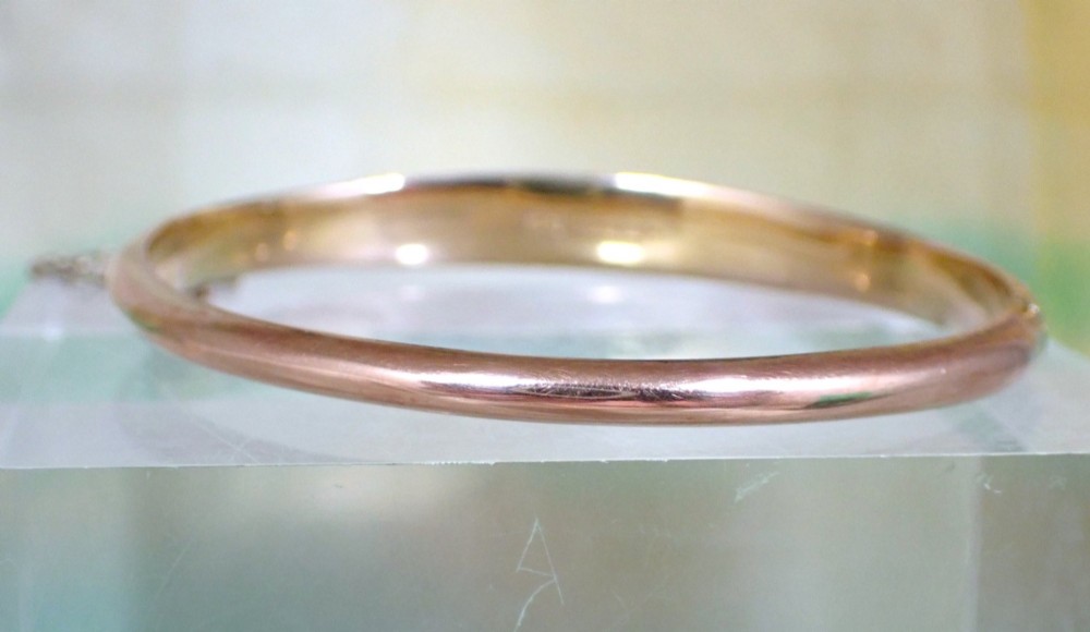 An antique Victorian hinged gold bangle featuring a textured honeycomb pattern across the upper band with a side safety chain. View IX