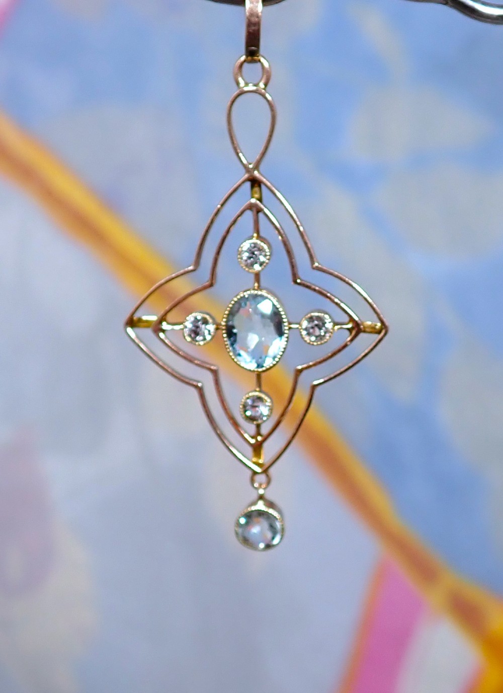 An openwork 9ct gold Edwardian pendant set with a central oval aquamarine, white sapphires, and a suspended aquamarine drop.