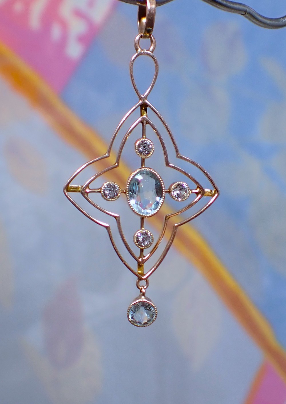 An openwork 9ct gold Edwardian pendant set with a central oval aquamarine, white sapphires, and a suspended aquamarine drop. View II